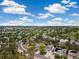 Wide aerial shot of a residential area with green trees and manicured lawns beneath a bright blue sky with clouds at 24422 E Frost Dr, Aurora, CO 80016
