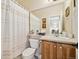 A well-lit bathroom with a toilet, sink, vanity, and shower with curtain at 24422 E Frost Dr, Aurora, CO 80016