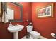 Elegant powder room featuring red walls, decorative mirror, and stylish fixtures at 24422 E Frost Dr, Aurora, CO 80016