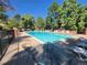 Community pool surrounded by lounge chairs and lush trees under a bright blue sky at 1920 S Hannibal St # B, Aurora, CO 80013