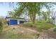 Exterior view of the home featuring lush backyard with mature trees, blue garage door and brick accents at 7780 Osceola St, Westminster, CO 80030