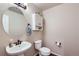 Half bathroom featuring a pedestal sink, toilet, and decorative wall cabinet at 1104 Rumbling Sky Pl, Castle Rock, CO 80108