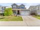 Charming gray two-story home featuring a well-manicured front lawn and a two car garage with stone accents at 7018 E 123Rd Pl, Thornton, CO 80602