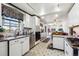 Bright kitchen with white cabinets, stainless steel appliances, granite countertops, and tile floors leading into the dining area at 9508 Lou Dr, Northglenn, CO 80260