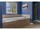 A luxurious soaking tub beneath a window offers a relaxing space with tiled surround and walls at 22665 E Calhoun Pl, Aurora, CO 80016
