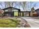 Striking modern home with sleek black siding, large windows, and a bright green accent wall at 1345 S Ivy Way, Denver, CO 80224