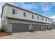 Exterior shot highlighting the gray siding, garage doors, and neatly maintained landscaping with a blue sky at 20530 E 58Th Ave, Aurora, CO 80019