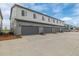 View of the building exterior featuring multiple garage doors with gray siding and light blue sky at 20530 E 58Th Ave, Aurora, CO 80019