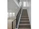 Modern staircase with black railings leading to the upper level, blending carpeted stairs with wood flooring at 20530 E 58Th Ave, Aurora, CO 80019