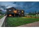 Exterior home view of a dark home with a backyard deck at dusk at 28364 Tresine Dr, Evergreen, CO 80439