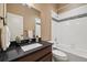 Stylish bathroom featuring an elegant dark countertop vanity, white toilet and tiled shower and tub at 1950 W 67Th Ave, Denver, CO 80221