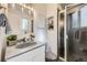Modern bathroom with a walk-in shower, granite sink, decorative mirror, and stylish vanity at 11617 W 71St Dr, Arvada, CO 80004