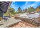 A spacious back patio complete with a hot tub and views of the partially snow-covered property at 29304 Thimbleberry Ln, Evergreen, CO 80439