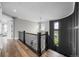 Elegant hallway with hardwood floors, dark railing, and a stylish light fixture at 6737 S White Crow Way, Aurora, CO 80016