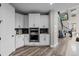 Kitchen with white cabinets, stainless steel appliances, geometric backsplash, and easy access to the staircase at 6737 S White Crow Way, Aurora, CO 80016
