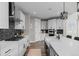 Bright open-concept kitchen features white cabinets, stainless steel appliances, and stylish black backsplash at 6737 S White Crow Way, Aurora, CO 80016