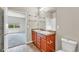 Bathroom featuring double sinks, wood cabinetry, and a view into an adjacent room with natural light at 12444 Madison Way, Thornton, CO 80241