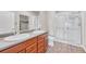 Bathroom featuring double sinks, a vanity with wood cabinets, and a tiled walk-in shower at 12444 Madison Way, Thornton, CO 80241