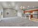 Open-concept living room featuring an elegant chandelier, bar seating, and a seamless flow to the kitchen with modern appliances at 12444 Madison Way, Thornton, CO 80241