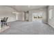 Open-concept living room with neutral paint, an elegant chandelier, bar seating, and a view to the front entrance and sunny sunroom at 12444 Madison Way, Thornton, CO 80241