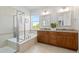Bright bathroom featuring a double vanity, tub, and glass-enclosed shower at 11343 E 163Rd Ct, Brighton, CO 80602