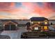Beautiful two-story home with a large front yard, detached garage, and an eye-catching sunset in the background at 11343 E 163Rd Ct, Brighton, CO 80602