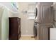Laundry room with stacked washer/dryer, shelving with toiletries, and a wooden cabinet at 11343 E 163Rd Ct, Brighton, CO 80602