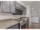 A modern kitchen with stainless steel appliances, granite countertops, and gray cabinets, next to laundry area at 6455 E Bates Ave # 4-105, Denver, CO 80222