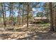 A view of the spacious backyard featuring mature trees, a wooden deck, playground, and lush greenery at 34103 Forest Park Dr, Elizabeth, CO 80107