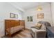 Cozy Bedroom with a wooden crib, a comfortable chair, hardwood floors, and a woven pendant light at 34103 Forest Park Dr, Elizabeth, CO 80107
