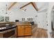 Open-concept living space featuring hardwood floors and a vaulted ceiling with wooden beams and a glimpse of the kitchen at 34103 Forest Park Dr, Elizabeth, CO 80107