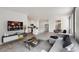 Open-concept living room with modern gray sofa, sleek entertainment center, and a view of the bright kitchen at 18120 Dandy Brush Ln, Parker, CO 80134