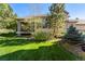 View of the backyard and house exterior, lush lawn, and mature trees at 3104 Ramshorn Dr, Castle Rock, CO 80108