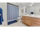 Well-lit bathroom featuring vanity with sink, a toilet, and a shower with a blue curtain at 3104 Ramshorn Dr, Castle Rock, CO 80108