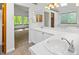 Bright bathroom featuring double sinks with white cabinetry, tub, and large window at 9174 Lark Sparrow Pl, Highlands Ranch, CO 80126