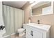Well-lit bathroom featuring a white vanity with dark hardware and shower with neutral shower curtain at 11022 Newark St, Commerce City, CO 80640