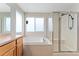 Bathroom featuring a tub, glass shower, bright window, and tiled surround for a clean, modern look at 11022 Newark St, Commerce City, CO 80640