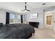 Bright main bedroom with a ceiling fan, two windows, a TV, and a view to the ensuite bathroom at 11022 Newark St, Commerce City, CO 80640