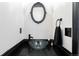 Stylish powder room with a glass bowl sink, decorative mirror, and modern black fixtures at 11022 Newark St, Commerce City, CO 80640