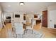 Open-concept dining room with hardwood floors, a glass table with seating, and a view into the kitchen and living area at 1553 Plowman Dr, Monument, CO 80132