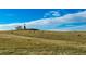 Picturesque pasture scene with grazing horses, a windmill, and a vast expanse of open land under a bright sky at 1431 Beacon Hill Dr, Highlands Ranch, CO 80126