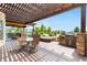 Outdoor living area with pergola, dining table, hot tub, and built-in grill, perfect for entertaining at 12665 S Robinson Ranch Ct, Parker, CO 80134