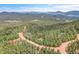 Aerial view of home with green roof surrounded by dense forest and mountains in the distance at 30122 Nancys Ln, Conifer, CO 80433
