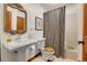Traditional bathroom featuring a pedestal sink, ornate mirror, and tiled shower with a patterned curtain at 30122 Nancys Ln, Conifer, CO 80433