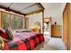 Bright bedroom featuring a four poster bed, view through the windows, and a cozy rug at 30122 Nancys Ln, Conifer, CO 80433