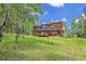 Wood sided home with a large deck and grass yard surrounded by aspen and pine trees at 30122 Nancys Ln, Conifer, CO 80433