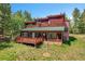 Back exterior of a wooden home with green roof and a wooden deck surrounded by lush greenery at 30122 Nancys Ln, Conifer, CO 80433