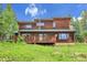 Wood sided home with a large deck surrounded by aspen and pine trees in a grass yard at 30122 Nancys Ln, Conifer, CO 80433