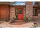 Charming red front door with brick surround and potted plants at 30122 Nancys Ln, Conifer, CO 80433