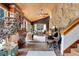 Inviting living room featuring a stone wall, wood ceiling, and large windows for natural light at 30122 Nancys Ln, Conifer, CO 80433